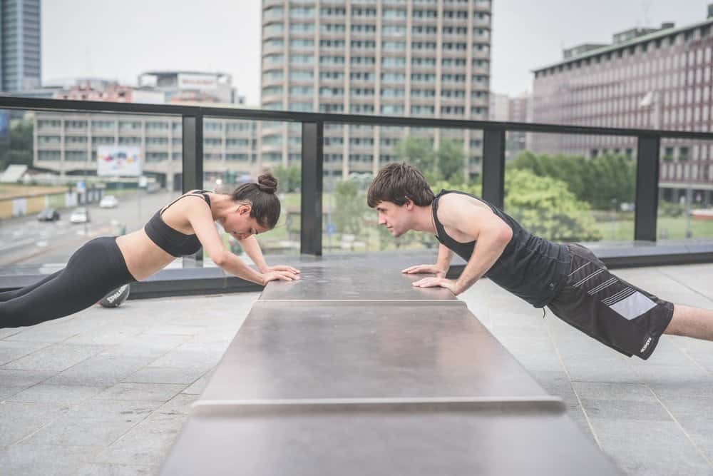 Couple of young handsome caucasian sportive man and woman doing push-ups, facing each other - sportive, fitness, healthy, training concept - HIIT for Weight Loss Training