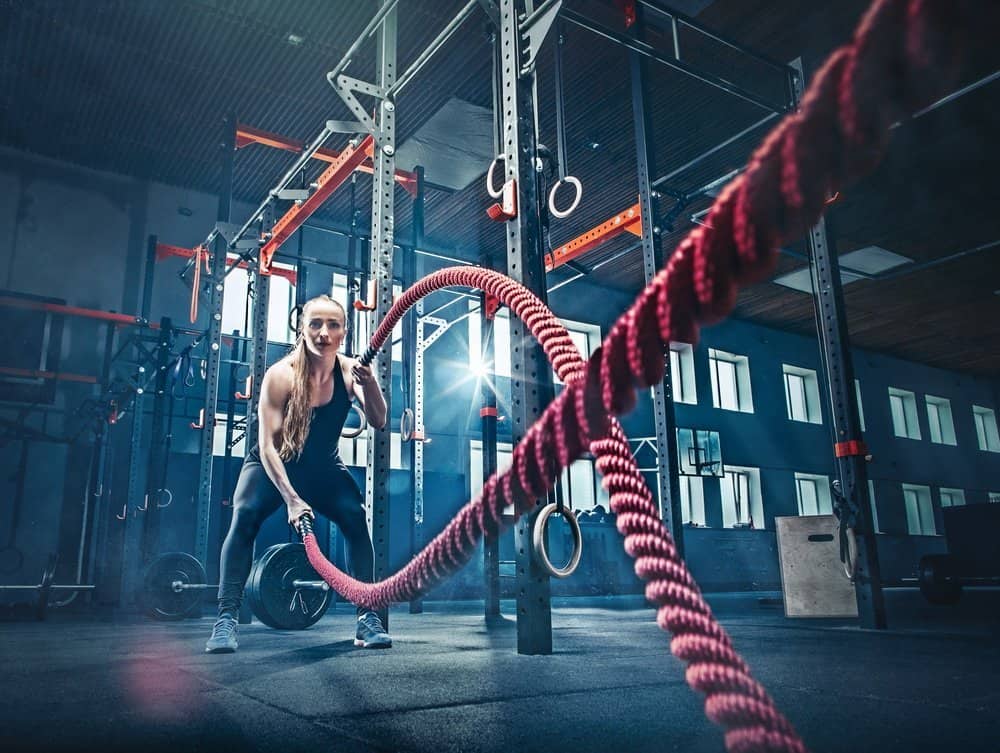 Woman with battle rope battle ropes exercise in the fitness gym. CrossFit concept. gym, sport, rope, training, athlete, workout, exercises concept - Top 10 Fitness Trends of 2019