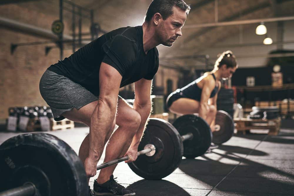 Sporty man and woman are about to lift barbells in gym - Lose Weight Naturally Fast