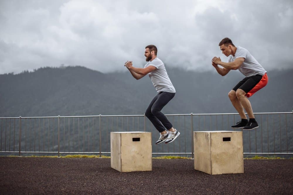 Two young male friends doing extreme box jumps - Plyometrics Workout - How to Boost Your Body’s Fitness Level and Avoid The Risk of Injury. The Ultimate Guide in Cross-Training.Two young male friends doing extreme box jumps - Plyometrics Workout - How to Boost Your Body’s Fitness Level and Avoid The Risk of Injury. The Ultimate Guide in Cross-Training.