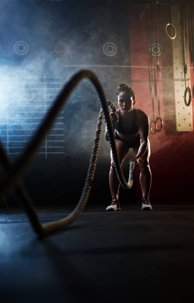 Sporty woman working out with ropes in gym - HIIT for Weight Loss Training