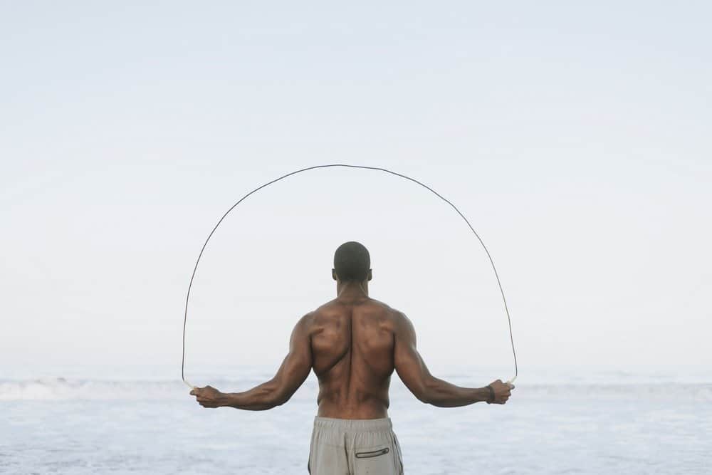 Fit man jumping rope at the beach - HIIT for Weight Loss Training