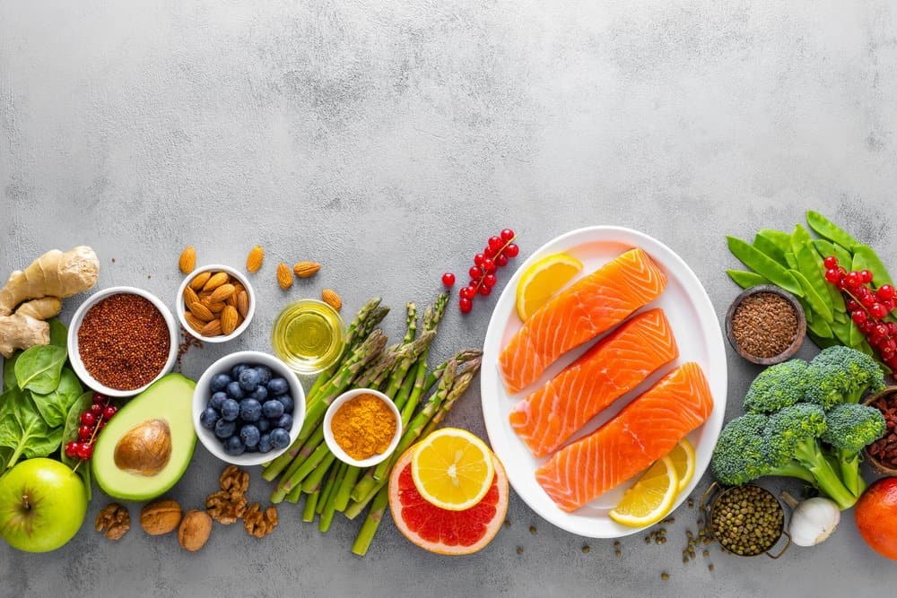 Healthy food background, salmon fish, spinach, quinoa, apple, blueberry, asparagus, turmeric, red currant, broccoli, mung bean, walnuts, grapefruit, ginger, avocado, almond, and green peas, top view