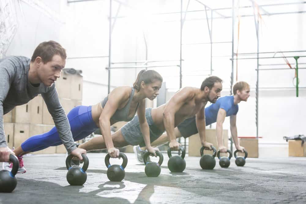 Dedicated people doing pushups with kettlebells at crossfit gym - Top 10 Fitness Trends of 2019