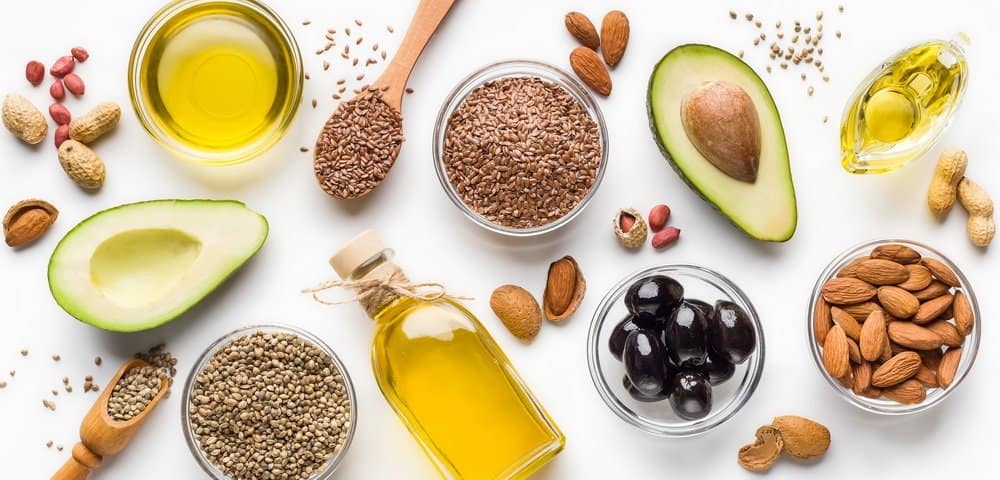 Avocado, almonds, hemp seeds, linseeds, olives and oils over white background, top view. Alternative oils concept - Side Effects from Keto Diet