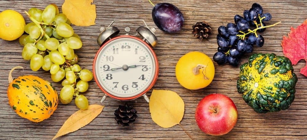 Autumn background with clock,pumpkin, apples and grapes.Autumnal concept.Harvesting