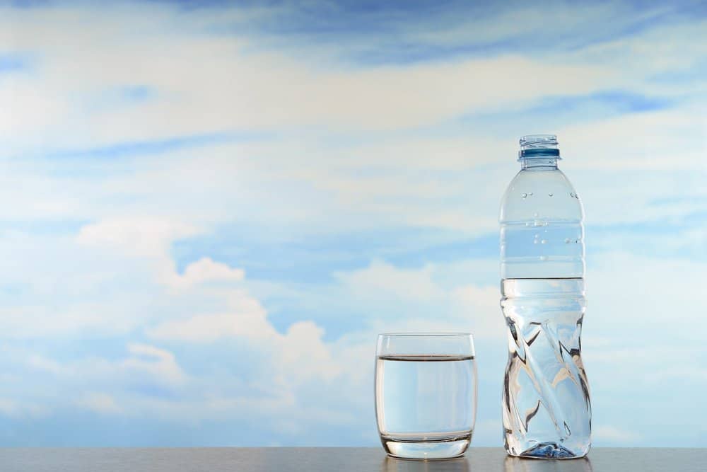 Fresh and clean drinking water in bottle and glass on sky background - A Natural Way to Detox Your Body