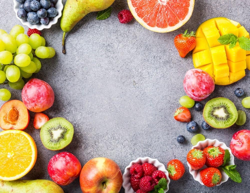 Fresh assorted fruits and berries on light gray background. Colorful clean and healthy eating. Detox food. Copy space. Top view.