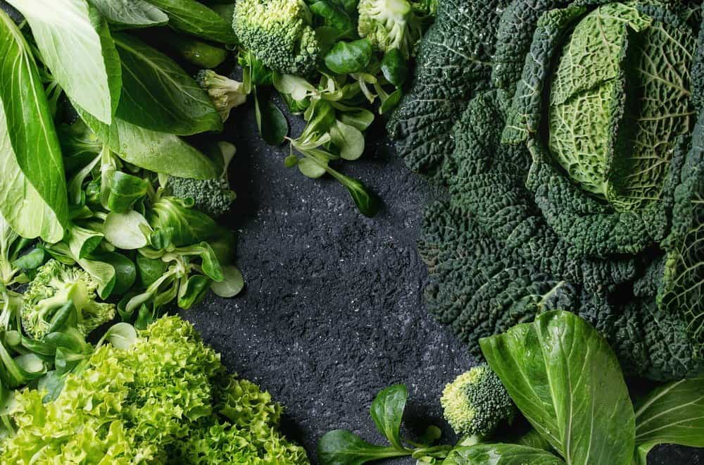 Variety of raw green vegetables salads, lettuce, bok choy, corn, broccoli, savoy cabbage as frame over black stone texture background. Top view, space for text - Diet Smoothies for Weight Loss