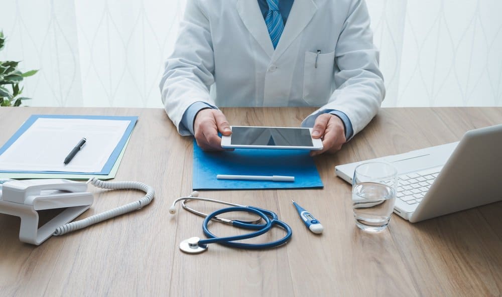 Professional doctor working at office desk, he is using a digital tablet, healthcare and technology concept - Benefits in Wearable Technology