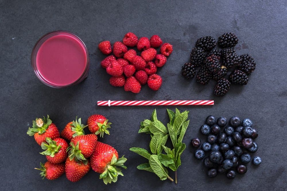 ingredients for perfect berry smoothie, flat lay overhead on dark slate - Diet Smoothies for Weight Loss