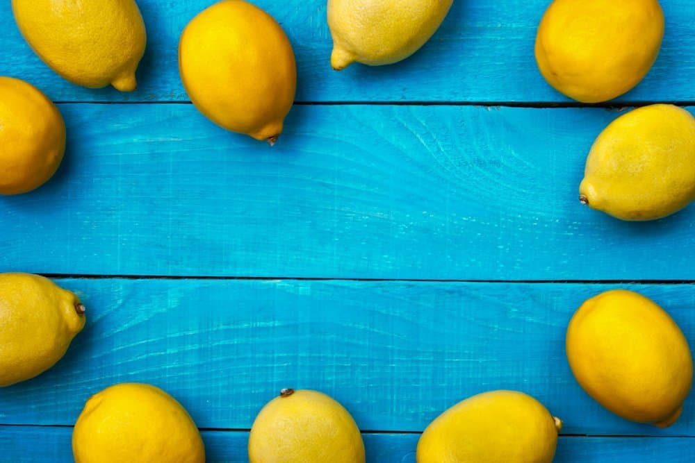 Yellow colorful lemons on the bright cyan wooden table horizontal - Organifi Green Drink Review