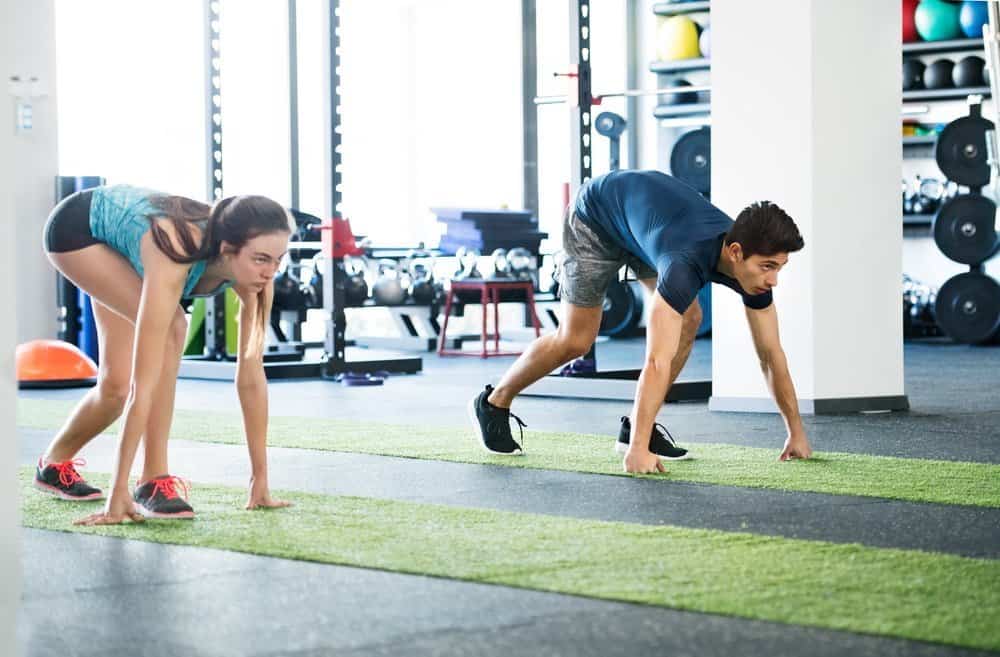 Runners in starting position. Young man and woman prepared for intense training session. Sports training in the gym. - Low Intensity Interval Training Workout