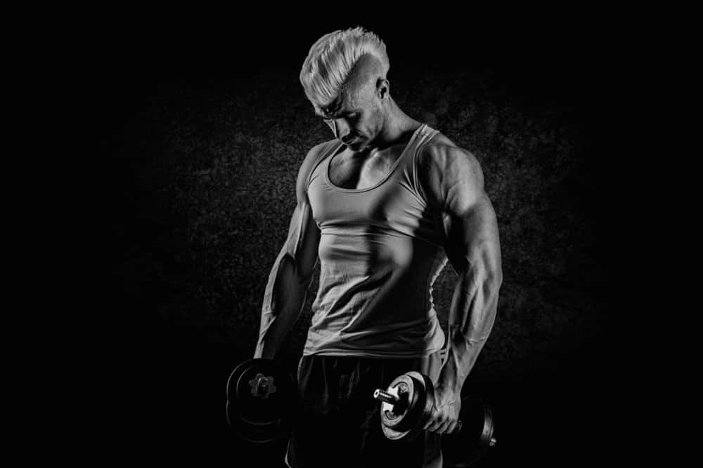 man posing while lifting dumbells - Best Strength Training Workout