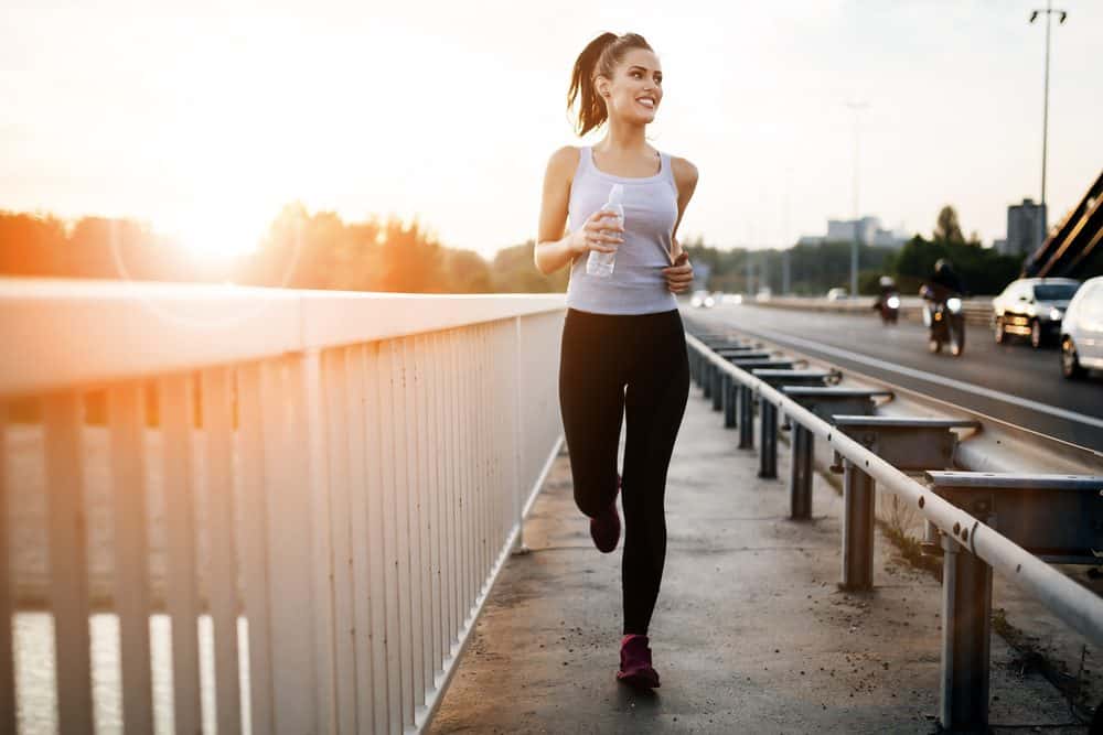 Young woman running over bridge - How Frequently Should a Beginner Exercise Running to Achieve Best Results for the Body and Avoid Injuries Explained