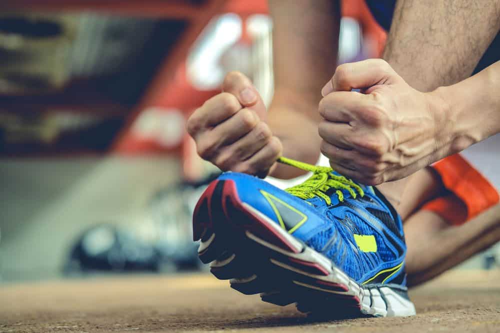 Athlete is tieing his shoelaces running shoes - Running Gear for Beginners