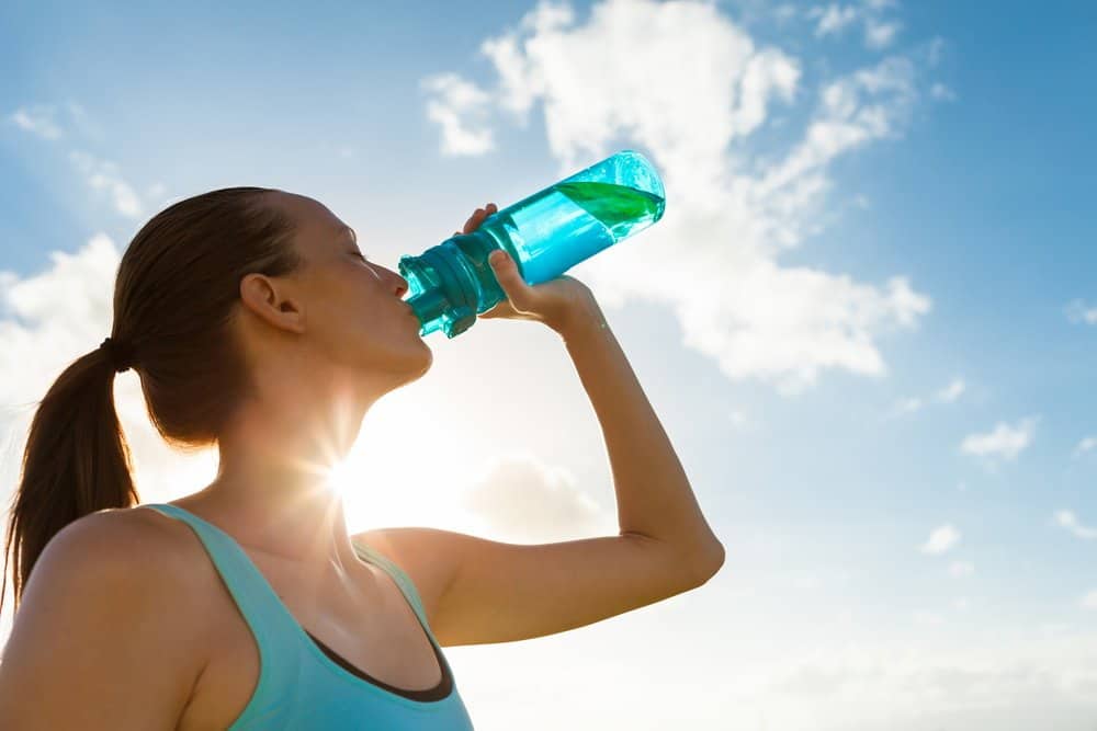 Young female drinking a bottle of water - How to Start Running as a Beginners