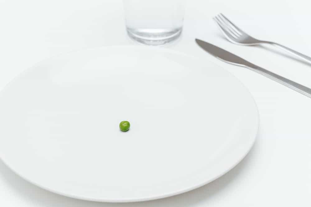 Plate with one small green pea on served table