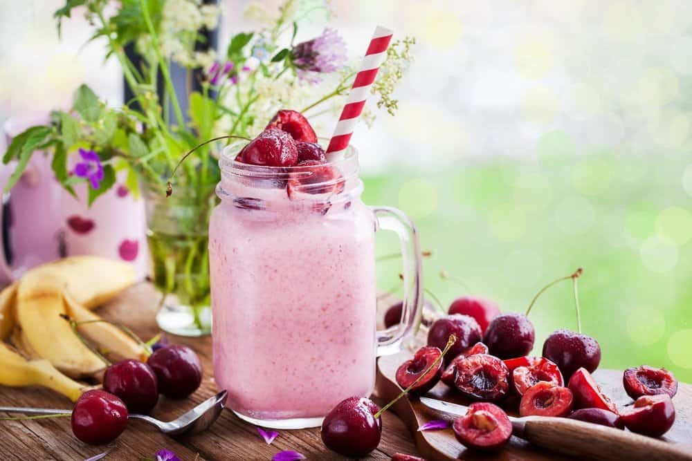 Fresh homemade healthy berry smoothie in mason jar on window background