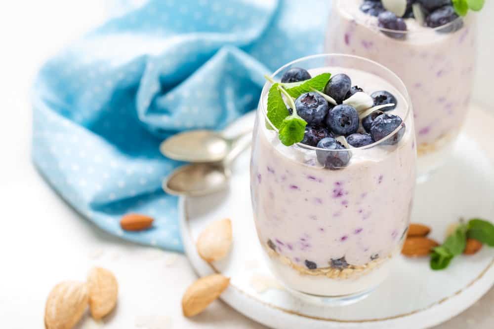 Greek yogurt or blueberry parfait with fresh berries and almond nuts on white background, healthy eating - Diet Smoothies for Weight Loss