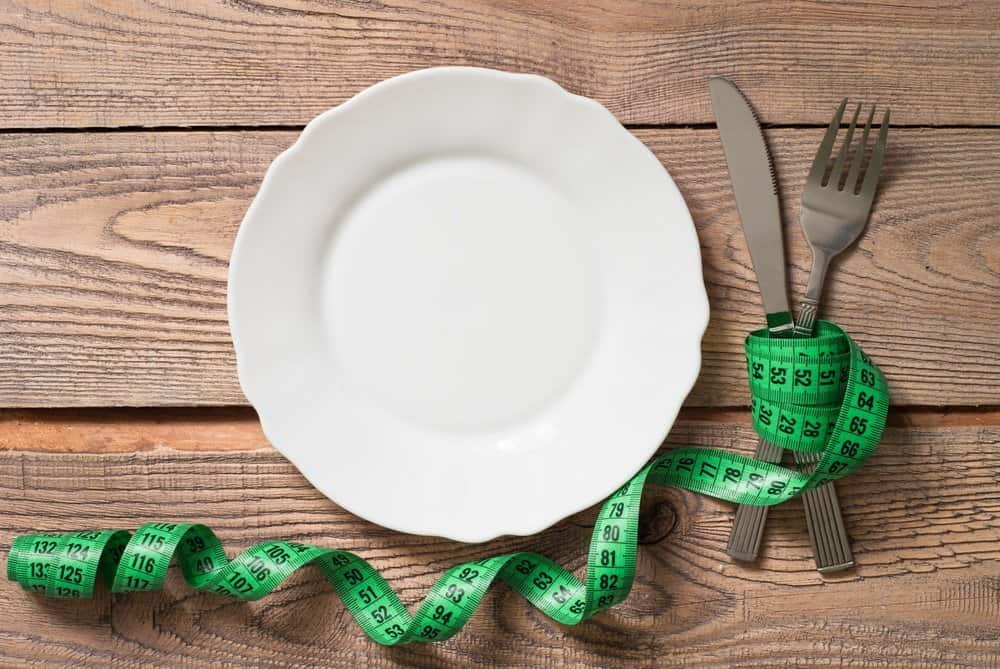 Healthy eating and Diet concept. Empty white Plate, fork, knife and measurement on wooden table.