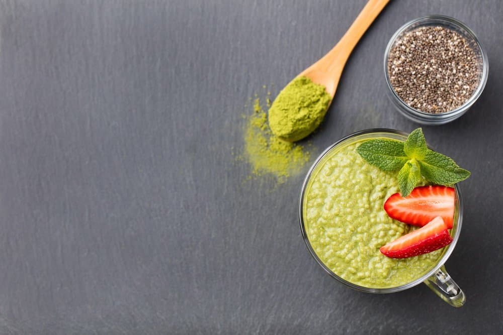 Matcha green tea chia seed pudding, dessert with fresh mint and strawberry on a black slate background. Healthy breakfast - Diet Smoothies for Weight Loss