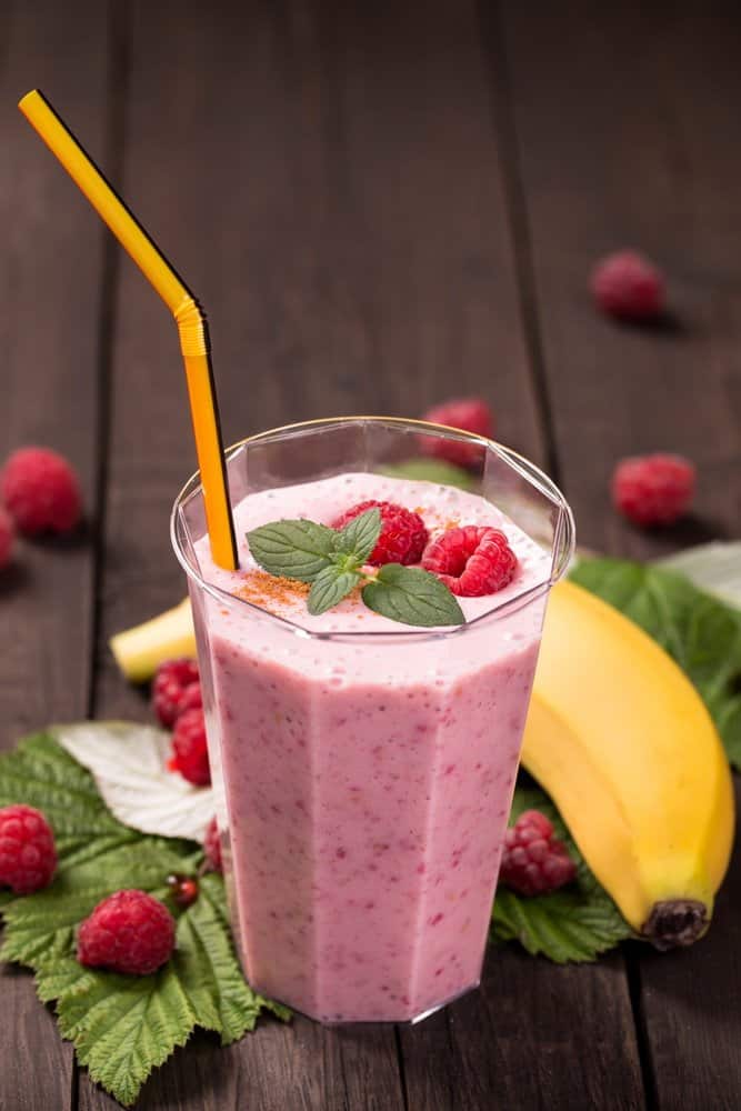 Glass of raspberry banana smoothie on wooden table - Diet Smoothies for Weight Loss