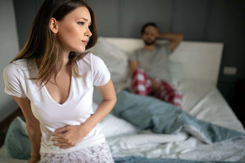 Sad, upset, unhappy woman holding hands on stomach suffering from abdominal pain - Side Effects from Keto Diet