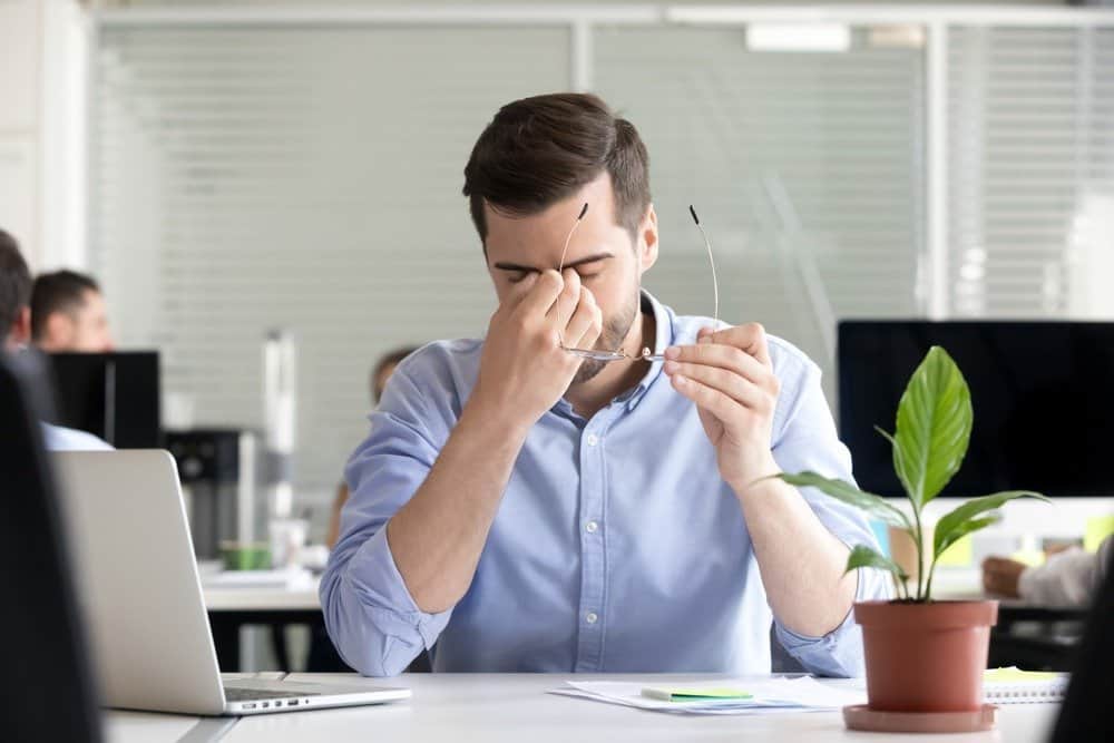 Tired businessman taking off glasses lost productivity - Signs You're Overdoing Cardio