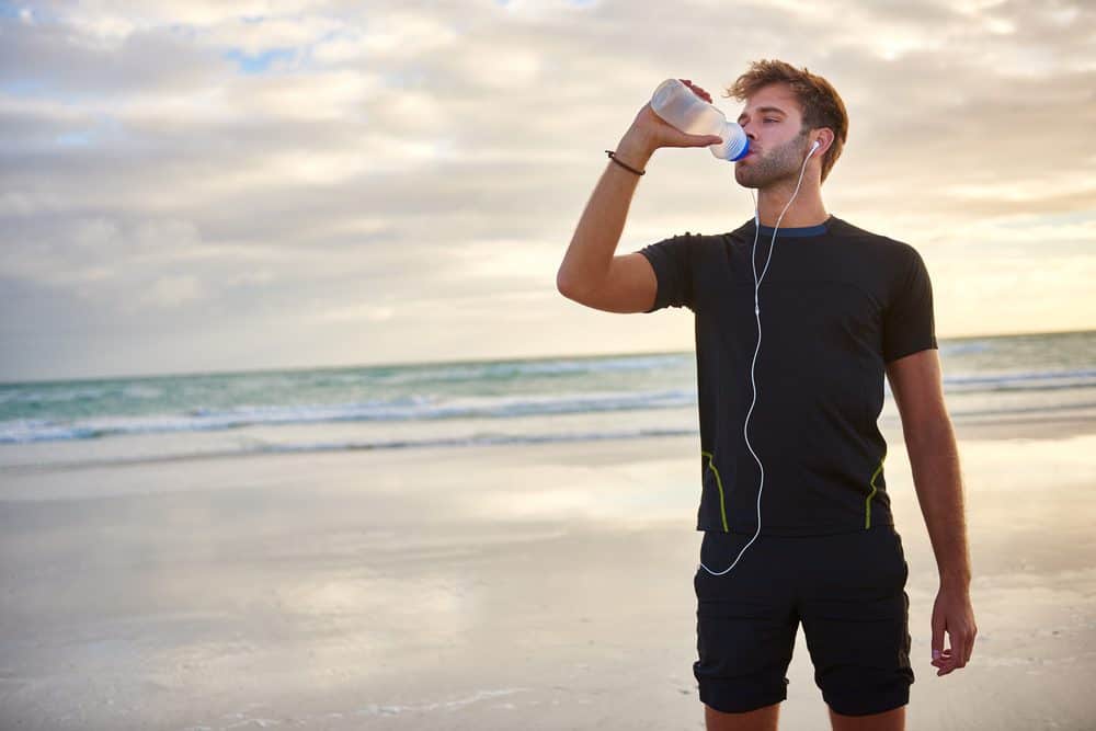 Young man looking fit and sporty drinking from his water bottle - 10 Reasons why Water is Important