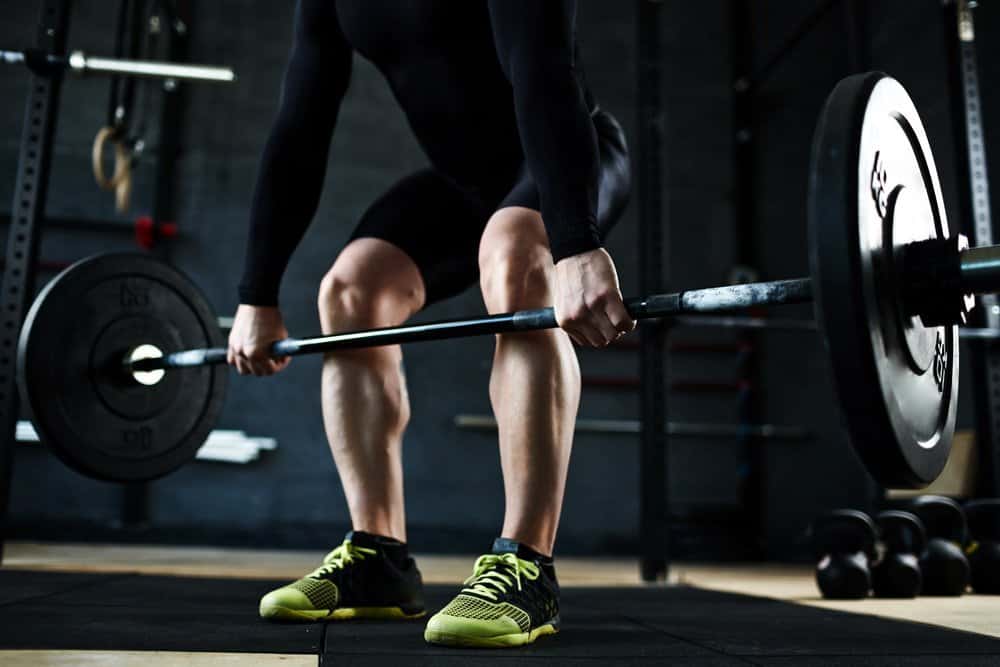 Hands of athlete lifting barbell in gym