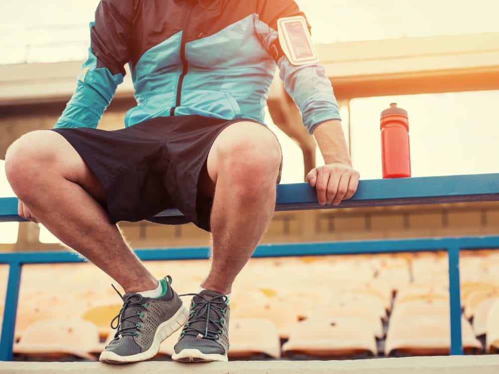 sportsman with a bottle of water sitting and resting at the railing at the stadium - 10 Reasons why Water is Important