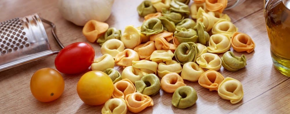 Italian food preparation. Colorful tortellini pasta, tomatoes and olive oil on the table, banner - Top 10 Ways to Weight Loss