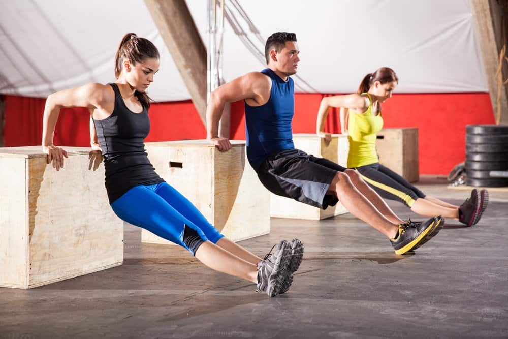 Young people exercising their arms using boxes in a cross-training gym - How to Boost Your Body’s Fitness Level and Avoid The Risk of Injury. The Ultimate Guide in Cross-Training.