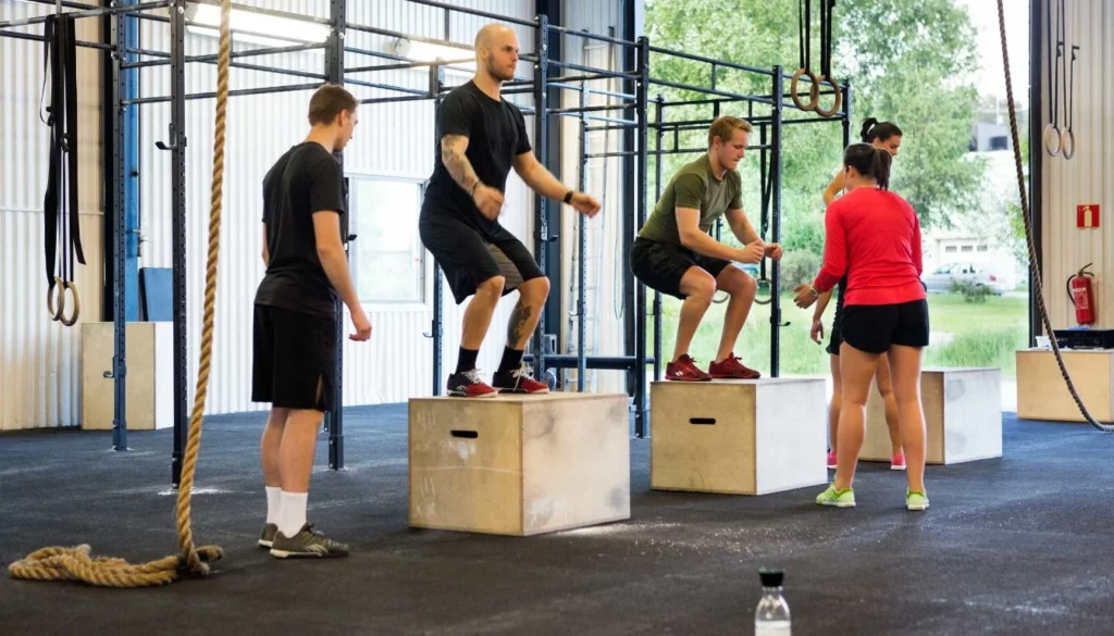 A group of people doing box jumps in a gym.