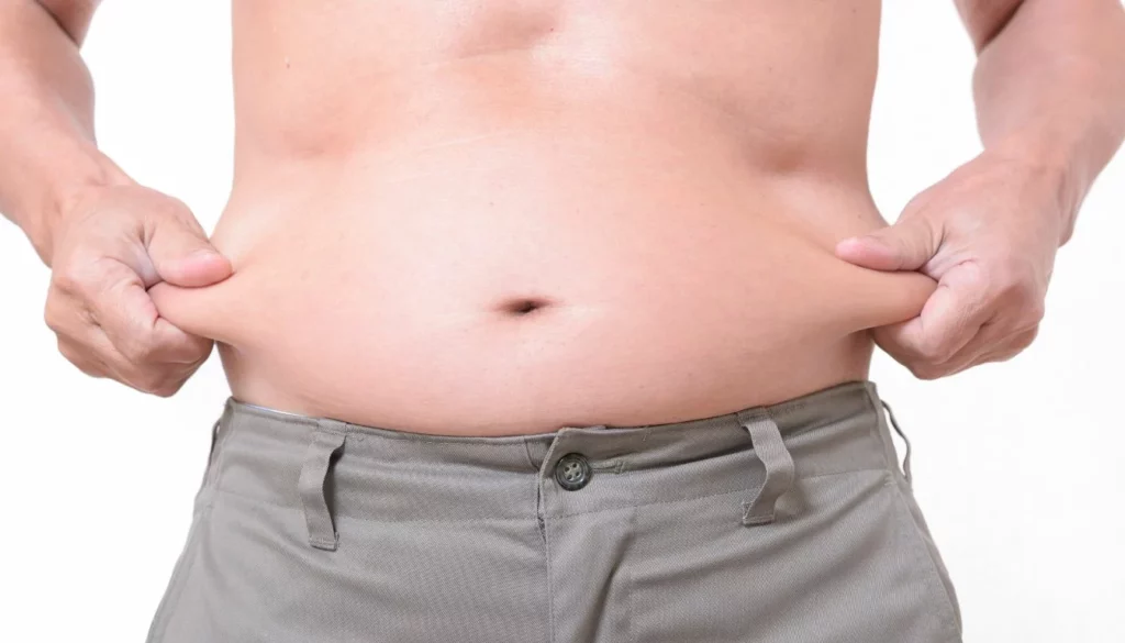 A man pinching his belly fat - Common Myths About Metabolic Age