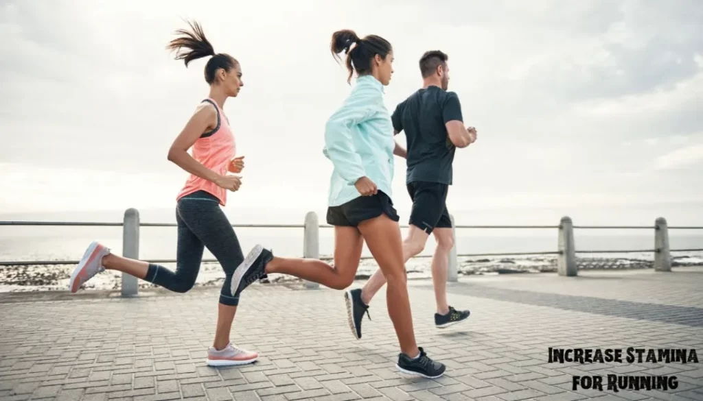 A group of three diverse runners jogging together on a seaside promenade.
