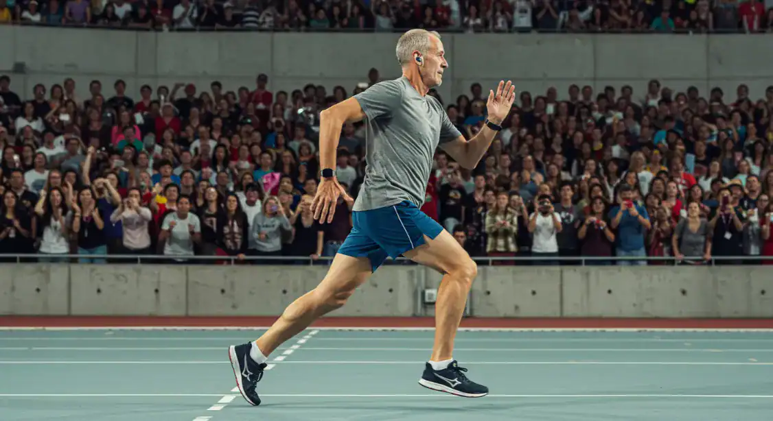 Man running on track, stadium crowd. Improve running technique.