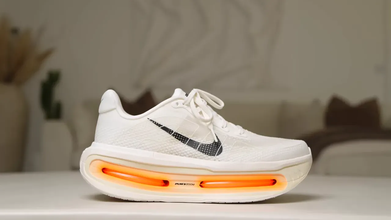 Side view of a white Nike running shoe with orange Air Zoom cushioning.