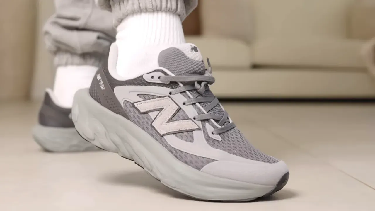 Close-up of a person wearing gray New Balance running shoe with white socks and gray sweatpants.