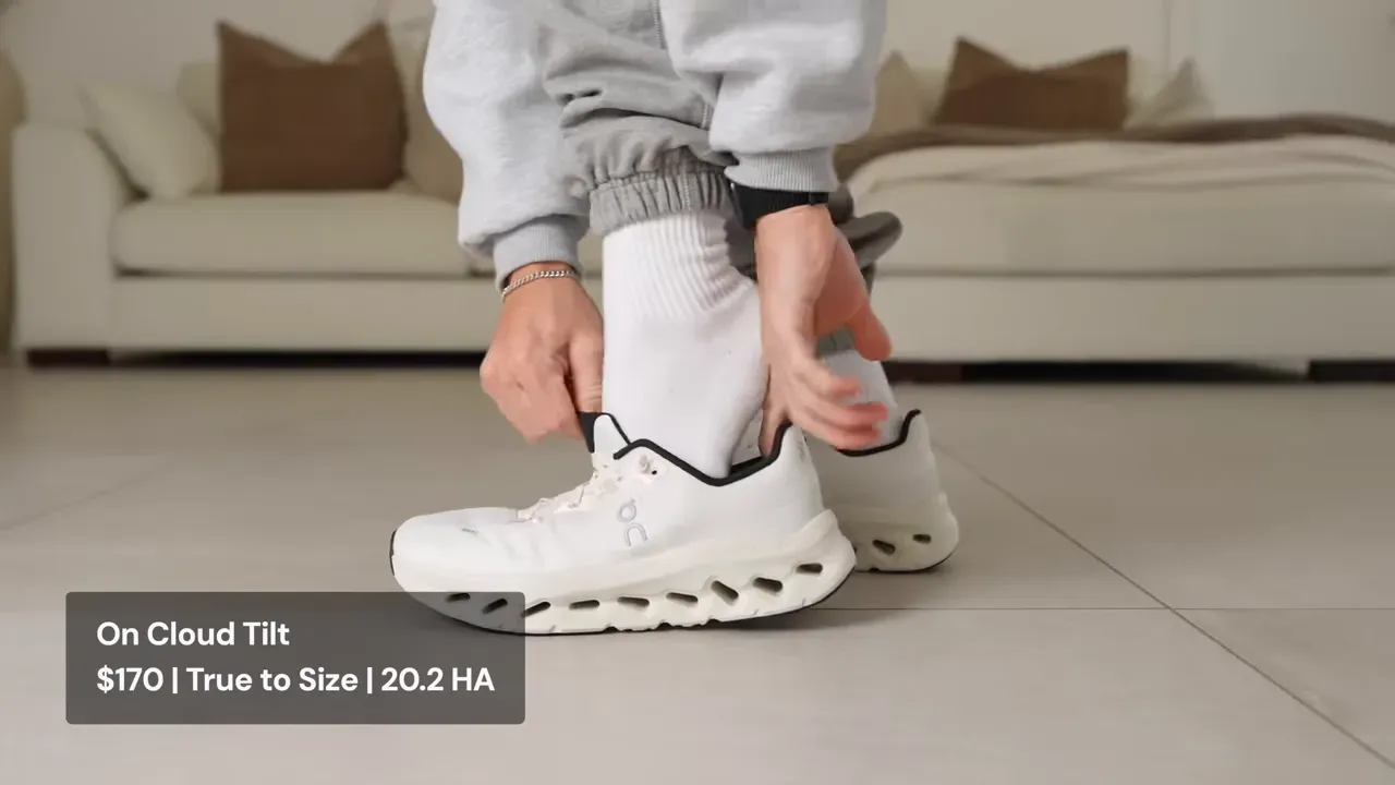 Person putting on white On Cloud Tilt running shoe with black trim. Close-up of hands and shoe.
