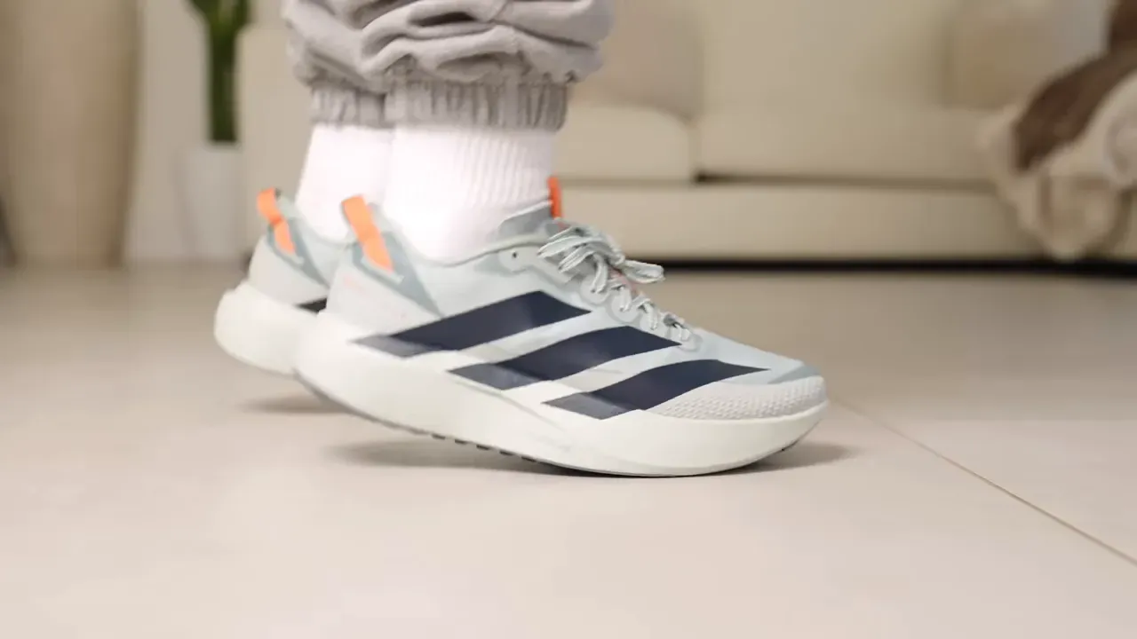 Person wearing Adidas running shoes, walking on a tile floor. Focus on shoe comfort.