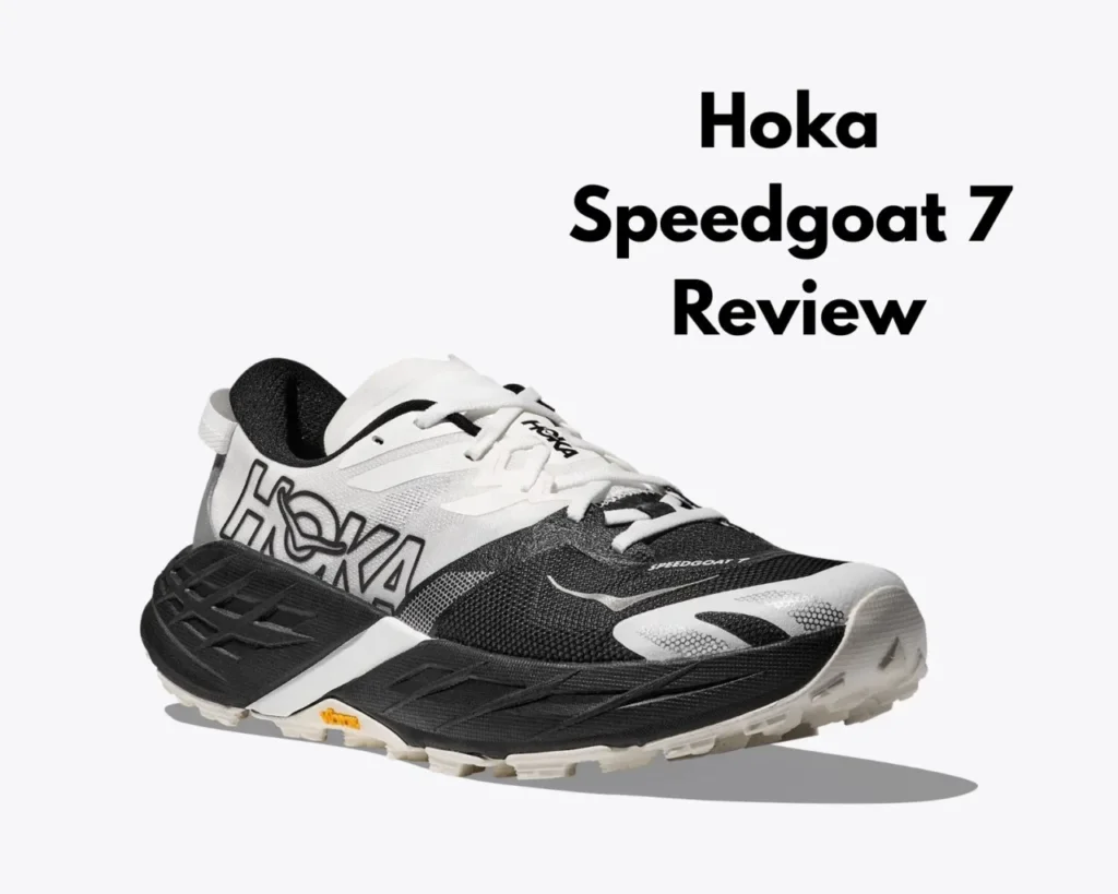 Close-up shot of a white and black Hoka Speedgoat 7 trail running shoe. The shoe features a Vibram Megagrip outsole and the Hoka logo. It is displayed on a text